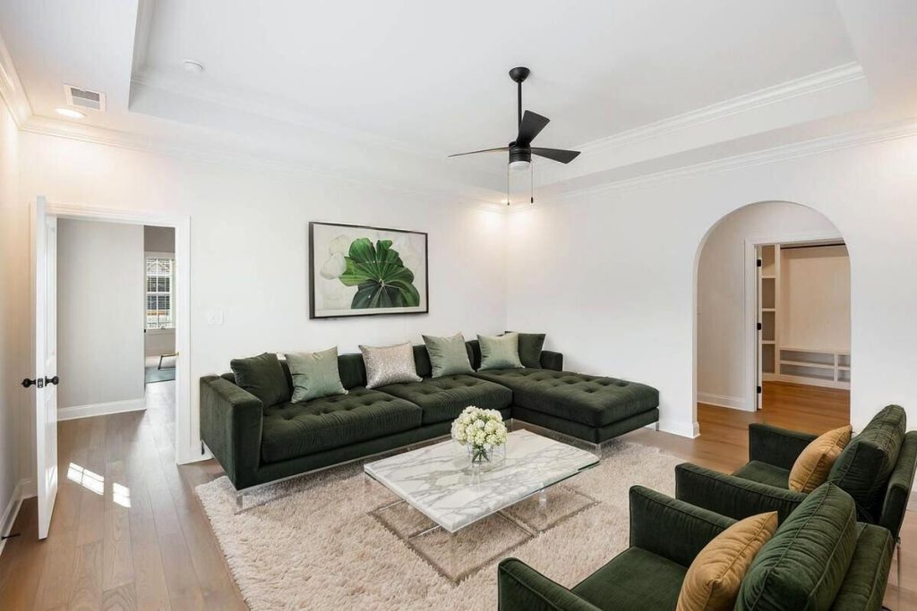 Modern living room transformed with AI virtual staging featuring deep green seating and contemporary décor.