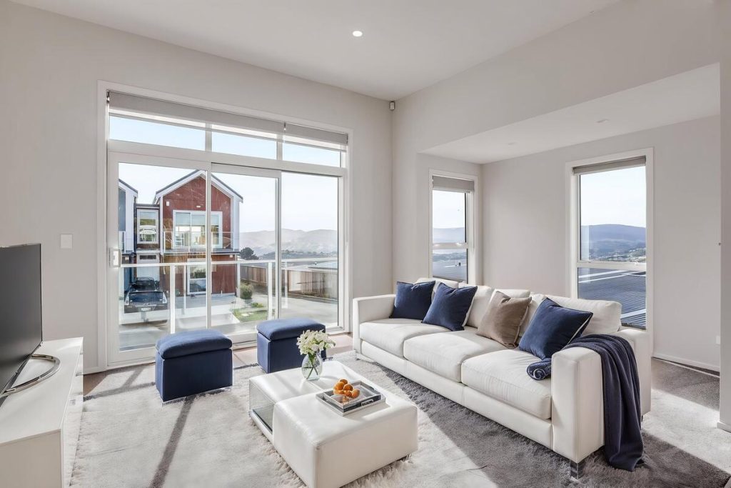 Best AI virtual staging example with white seating and navy decor in a bright living room.