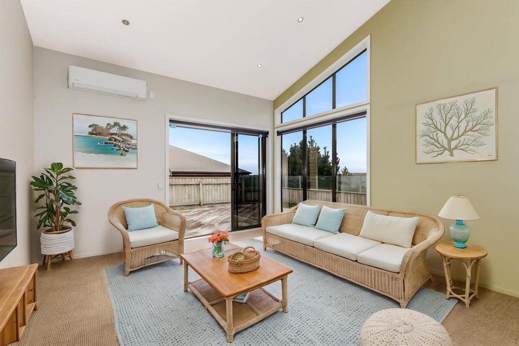 Best AI virtual staging example of a coastal living room with blue seating and wicker furniture.