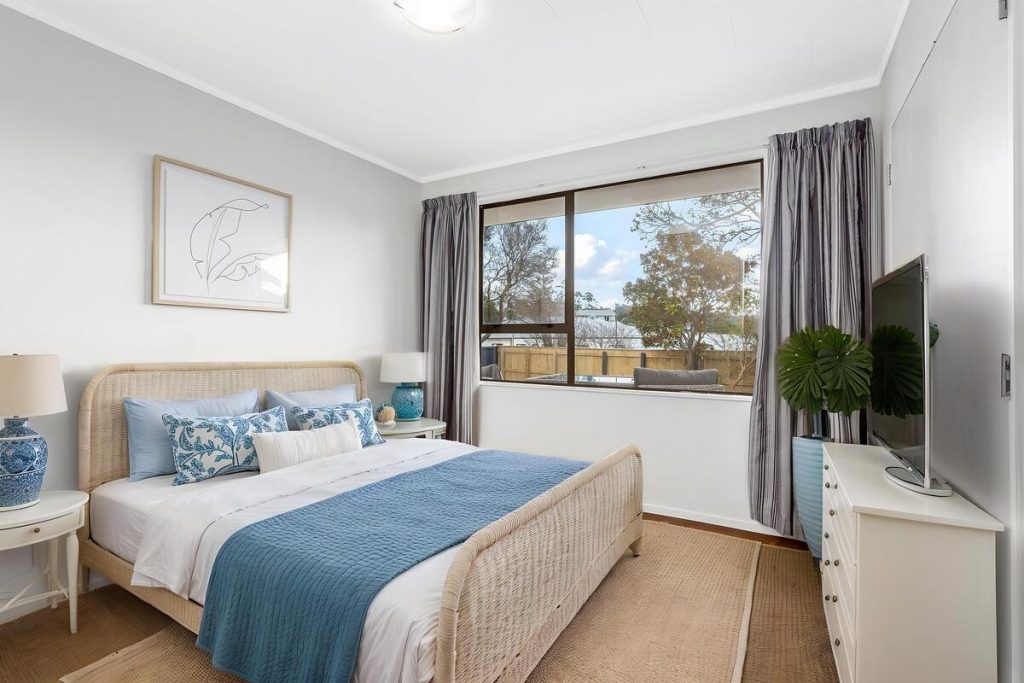 Best AI virtual staging example of a coastal bedroom with blue bedding and rattan furniture.