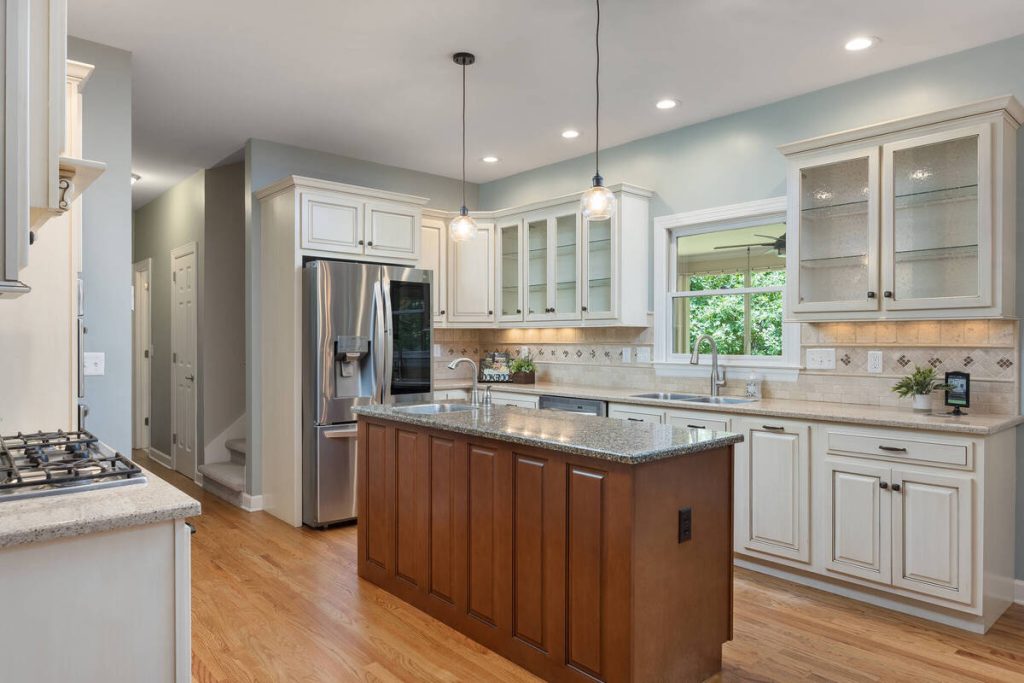 AI real estate photo editing showcasing a bright kitchen with white cabinets and a large center island.