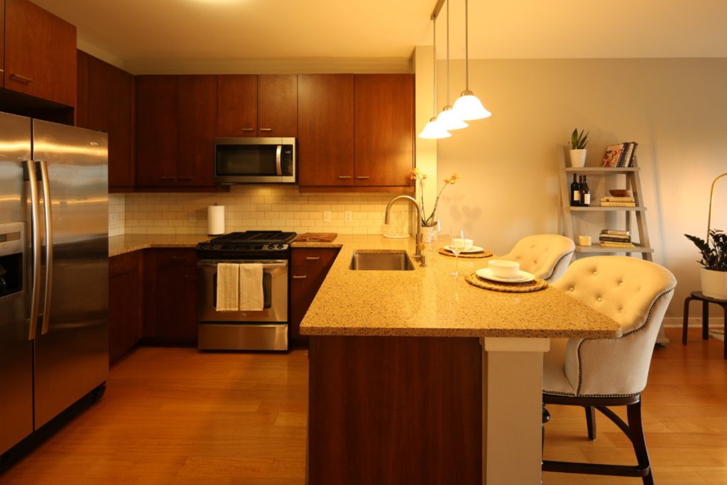 Kitchen before AI real estate photo editing with warm color cast and uneven lighting.