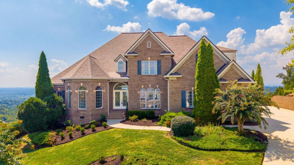 Real estate photo editor enhancing a luxury brick home exterior