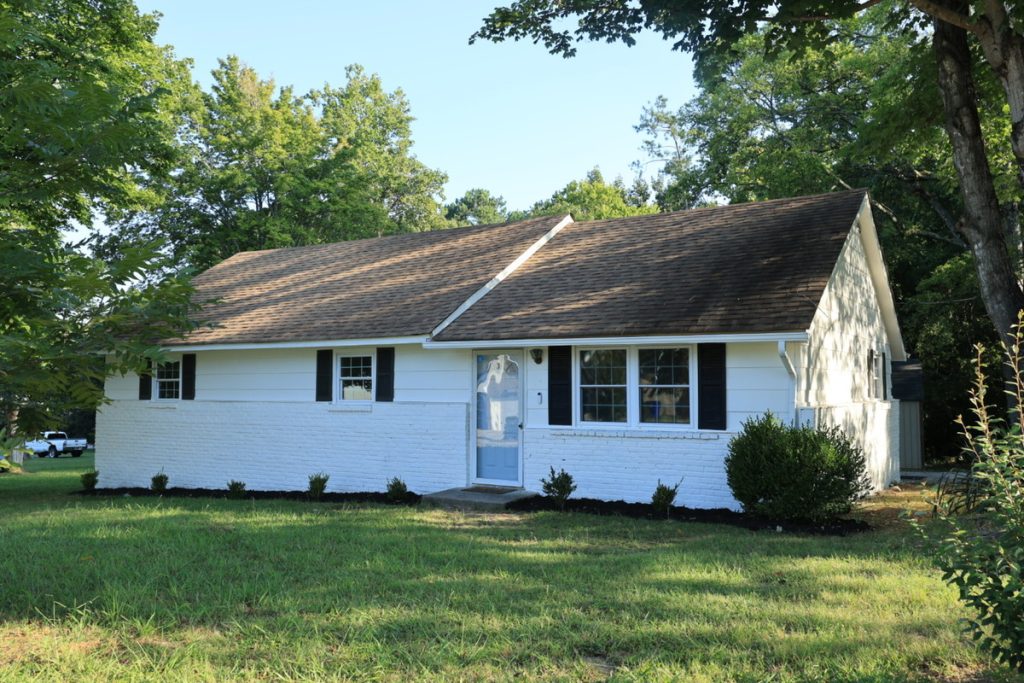 Real estate photo editor showing a small home exterior before enhancement