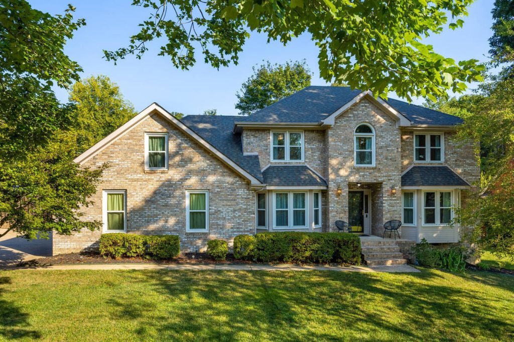 Real estate photo editor enhancing a brick home exterior with balanced lighting