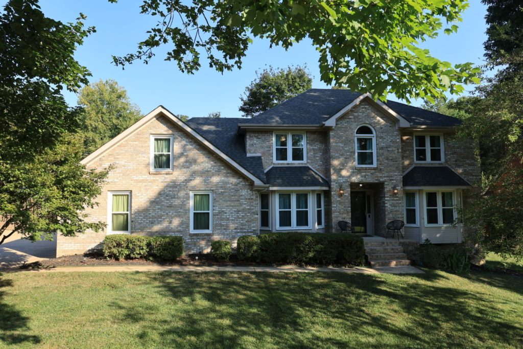 Real estate photo editor showing a brick home exterior before enhancement