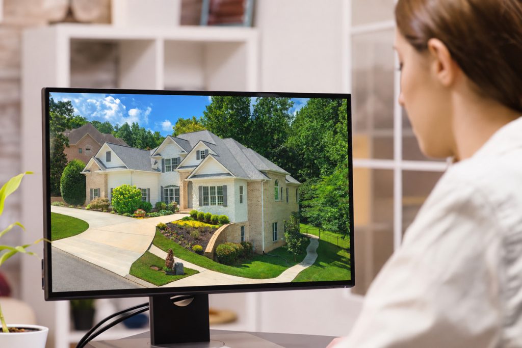 Real estate photo editor displaying an enhanced property exterior on a monitor