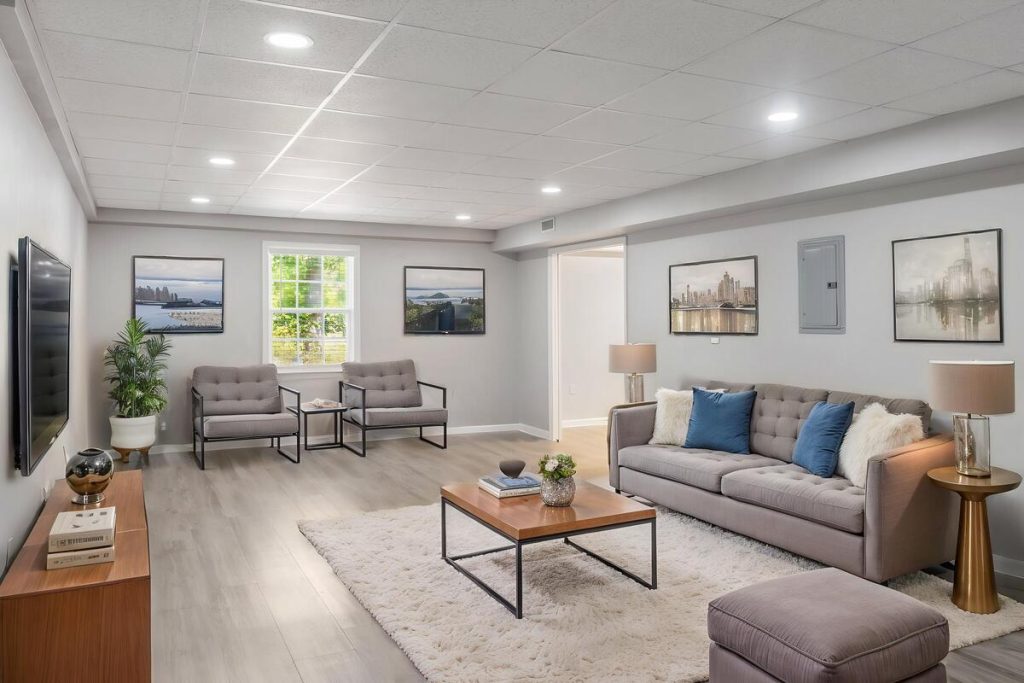 Real estate image editing featuring virtual staging in a spacious basement living room