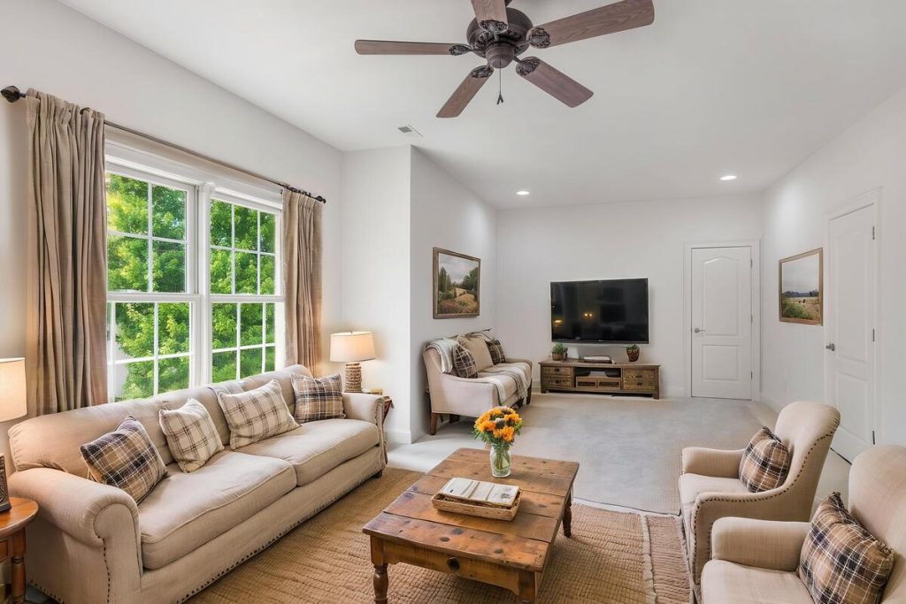 Virtually staged family room with neutral seating and rustic wood furniture using virtual staging software.